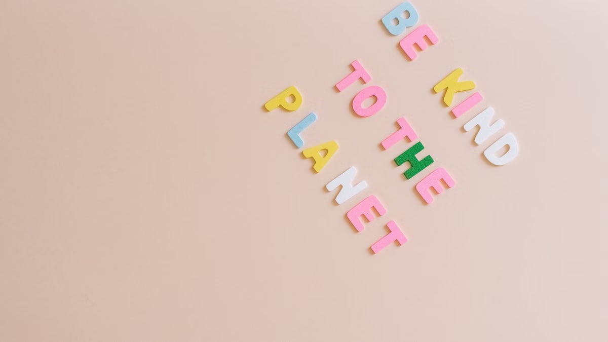 Colorful text on beige background promoting environmental awareness with 'Be Kind to the Planet'.